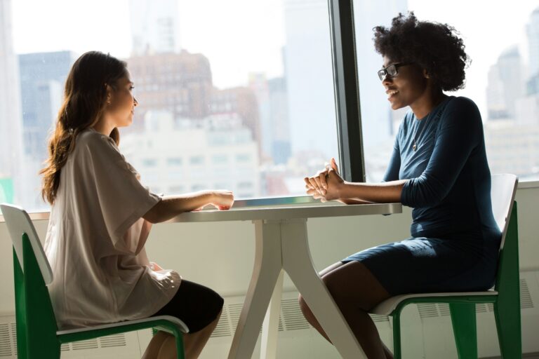 Two females talking over table
