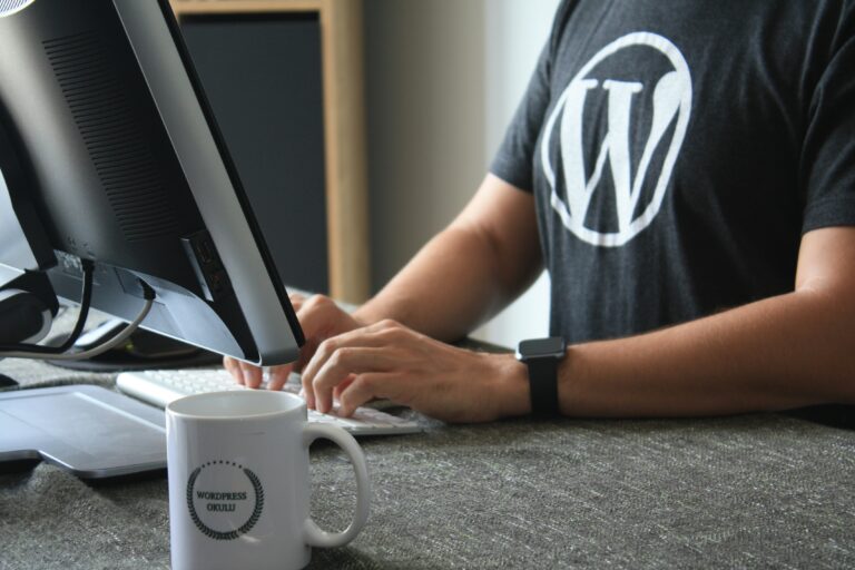 guy typing with WordPress shirt and WordPress mug